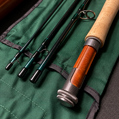Close-up of a fishing rod set laid on a green fabric rod roll, with black and teal rods and a cork-and-wood handled rod visible.