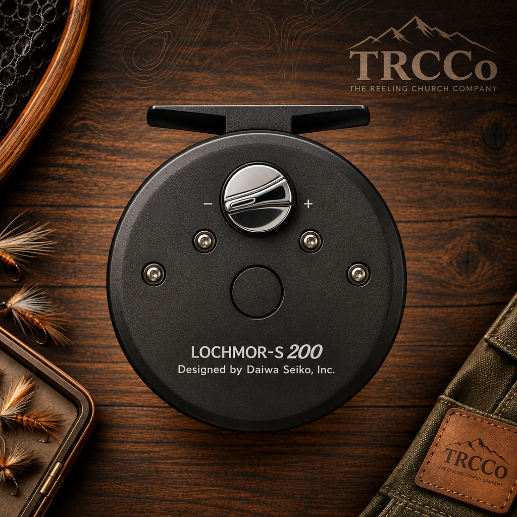 A black circular fly-reeling device labeled 'LOCHMOR-S 200' and 'Designed by Daiwa Seiko, Inc.' placed on a dark wood surface, with fishing flies, a rod handle, and a TRCCO pouch nearby.