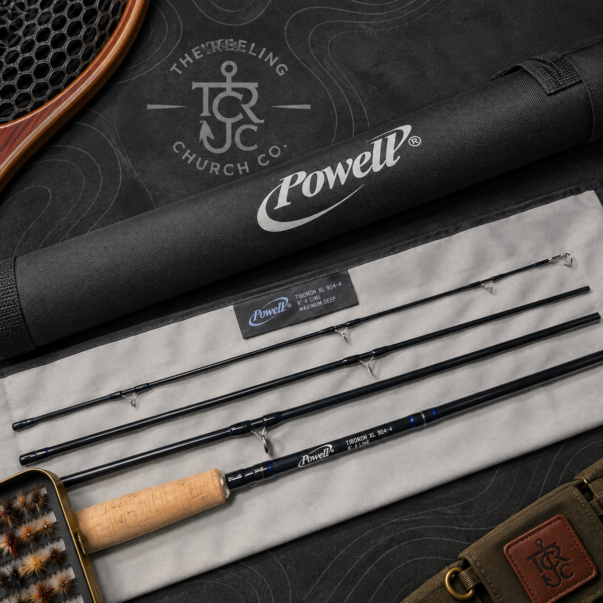 Powell fly fishing rod set displayed on a light gray fabric surface with its black carrying case, shown in a styled flat-lay arrangement with a paddle and leather strap nearby. The rod is black with blue accents and a cork handle.